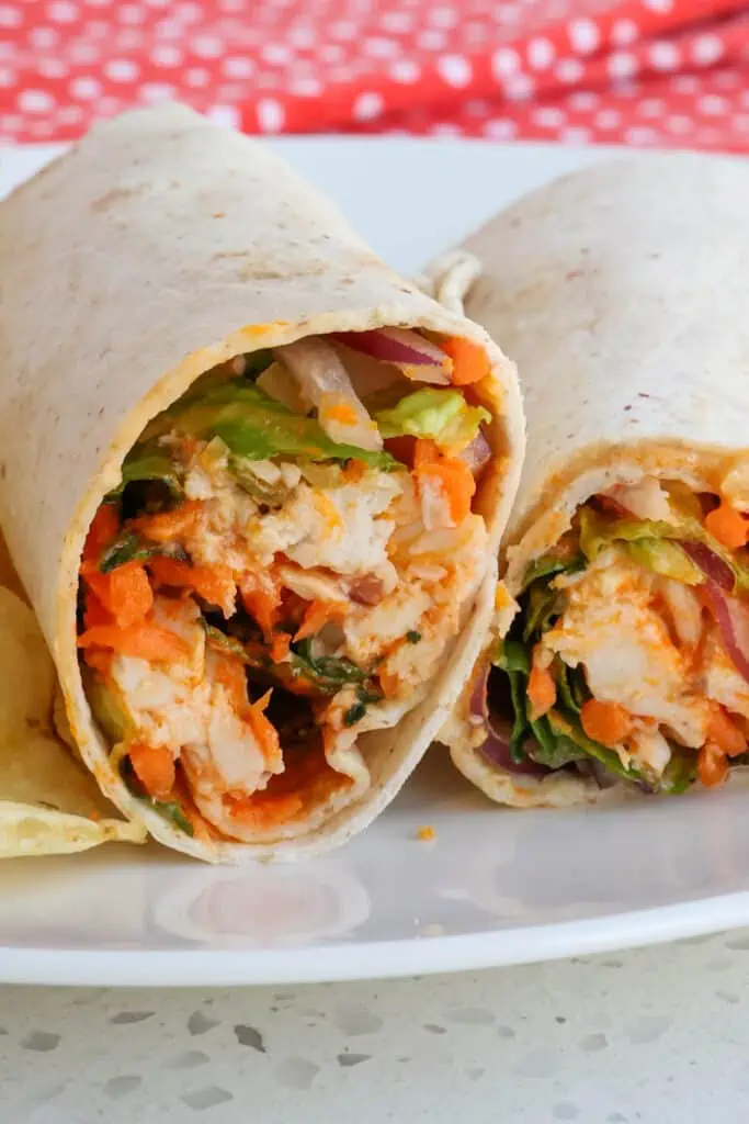 Quick and easy Buffalo Chicken Wraps bursting with the taste of buffalo wings, crisp romaine, sweet red onion, crunchy carrots, sharp cheddar, and ranch dressing. 