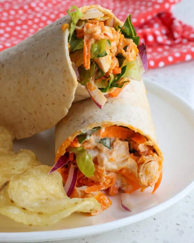 A stacked buffalo chicken wrap on a single serving white plate. 