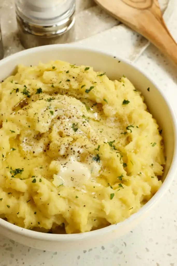 Red potatoes are mashed with sweet roasted garlic, butter, and cream and topped with fresh herbs for the ultimate comfort food side dish. 