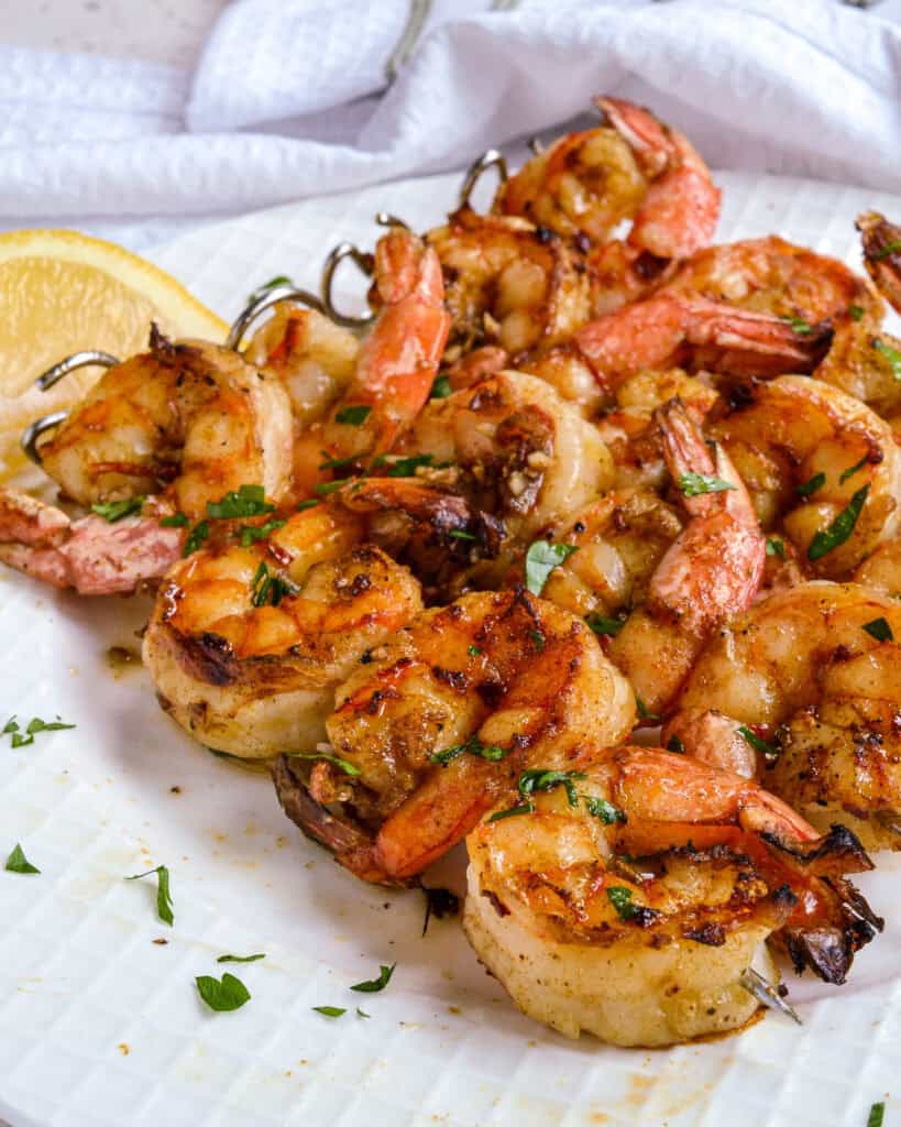 Grilled Shrimp on a white plate with a lemon wedge.