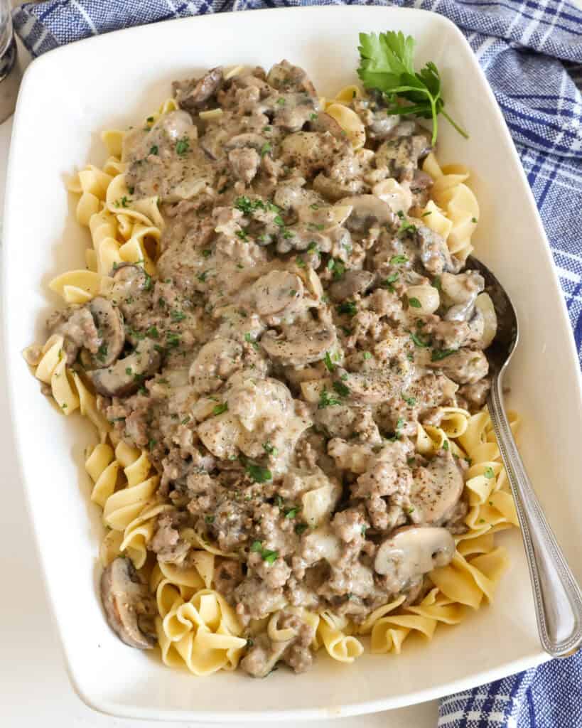 A large serving dish full of ground beef stroganoff over egg noodles.