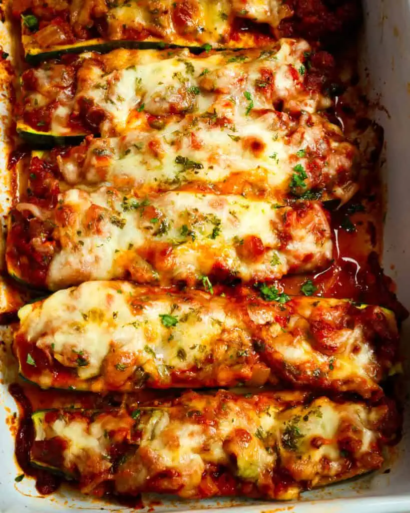 An overhead view of a rectangular casserole dish filled with zucchini boats stuffed with sausage, marinara, and cheese. 