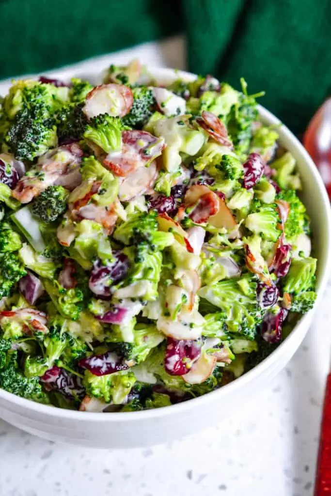 A family-friendly, easy broccoli salad recipe with crisp bacon, onions, sliced almonds, dried cranberries, and a lightly sweetened, easy four-ingredient dressing. 