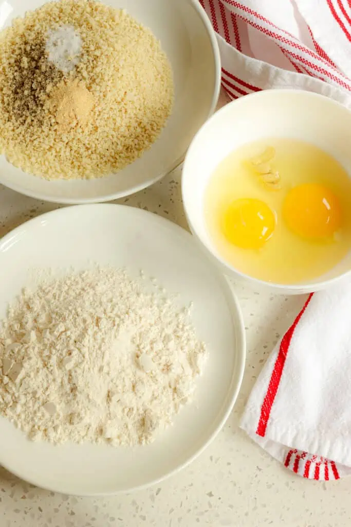 First setup the breading stations.  Add the flour to a rimmed plate or shallow bowl.  Then whisk together the eggs and Dijon Mustard together in a shallow bowl.  Combine the Panko Breadcrumbs, salt, black pepper, and garlic powder on another rimmed plate or in a shallow bowl. 
