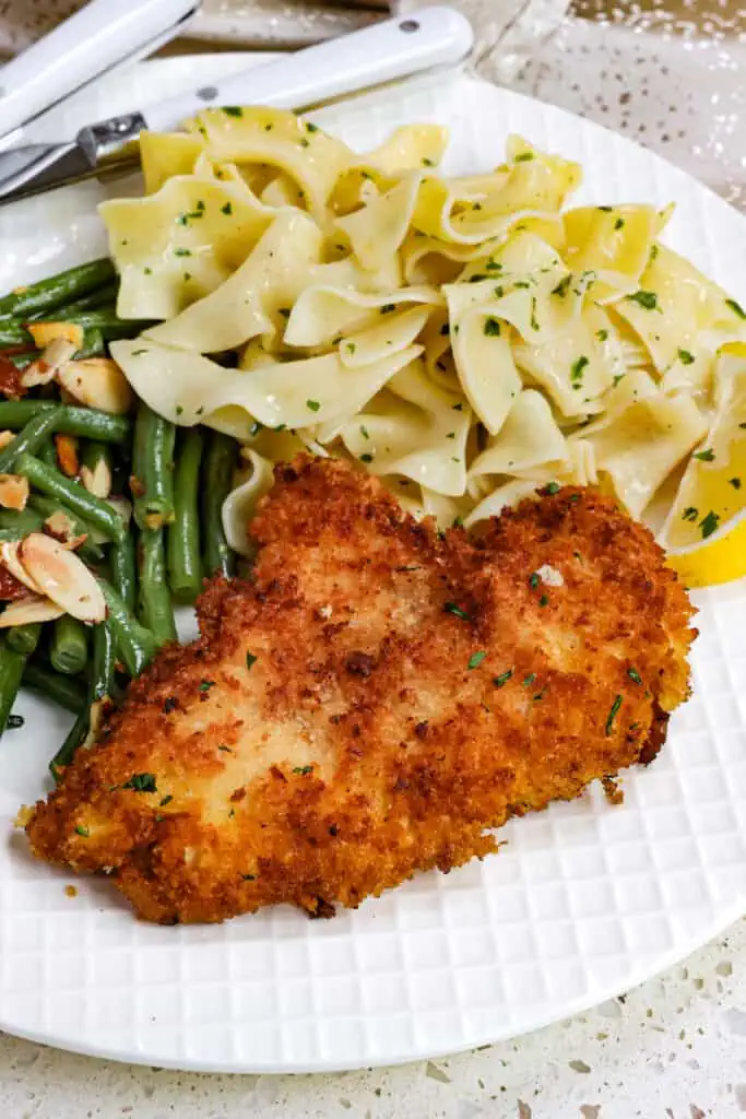 This Chicken Schnitzel recipe is breaded chicken cutlets pan fried to golden crispy perfection and served with lemon wedges and chopped fresh parsley.