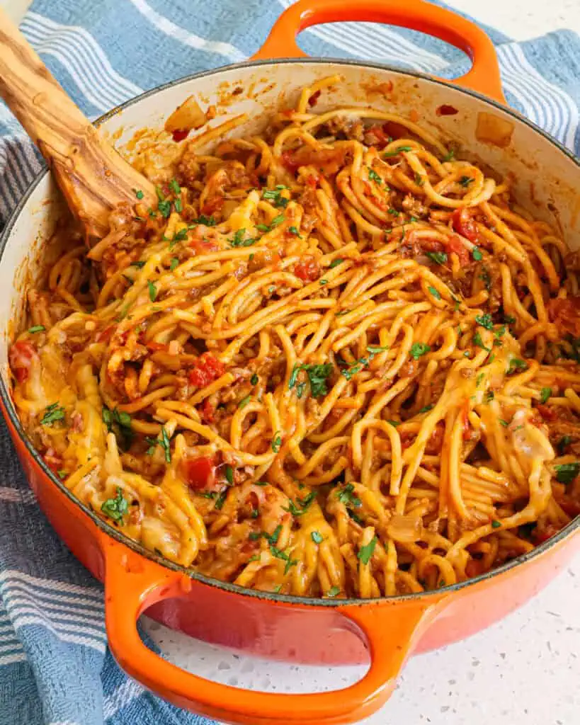 A Dutch oven full of quick and easy Taco Spaghetti is loaded with flavor from ground beef, onion, Rotel tomatoes, and taco seasoning.