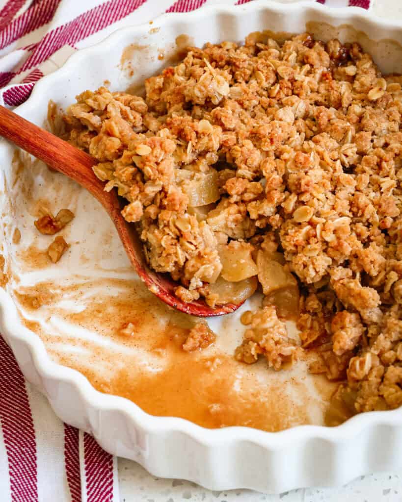 Best Apple Crisp Recipe Apple crisp in a baking with a wooden spoon.