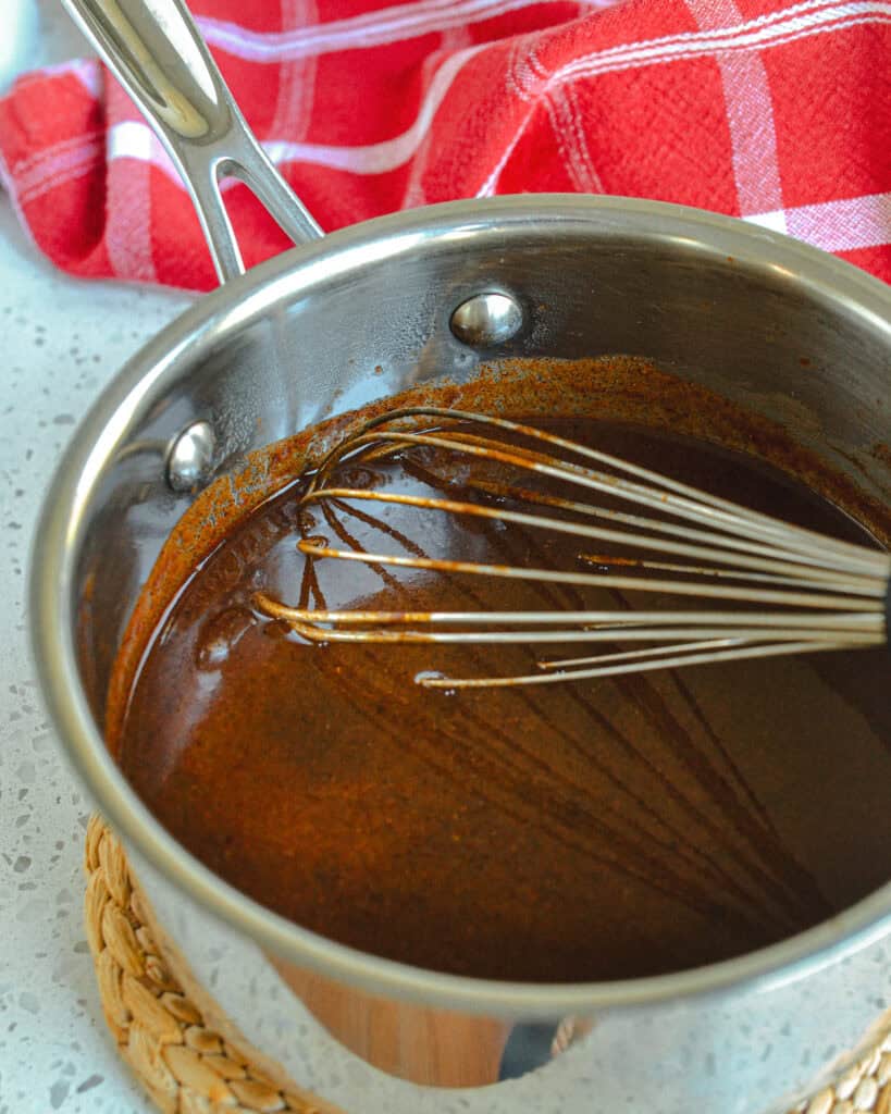 Enchilada Sauce in a saucepan with a whisk.