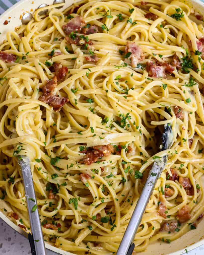 Pasta Carbonara in a large skillet with tongs.