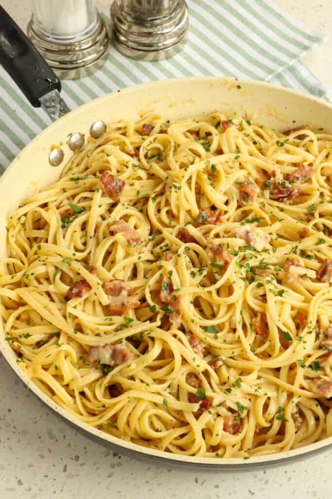 Pasta Carbonara is pasta mixed with thick pan-fried bacon or pancetta, a couple of tablespoons of the rendered fat, and a little bit of minced garlic. Then, a mixture of eggs, egg yolks, Parmesan, and a little cooking water is added and tossed quickly while the pasta is still very hot, creating a creamy sauce.