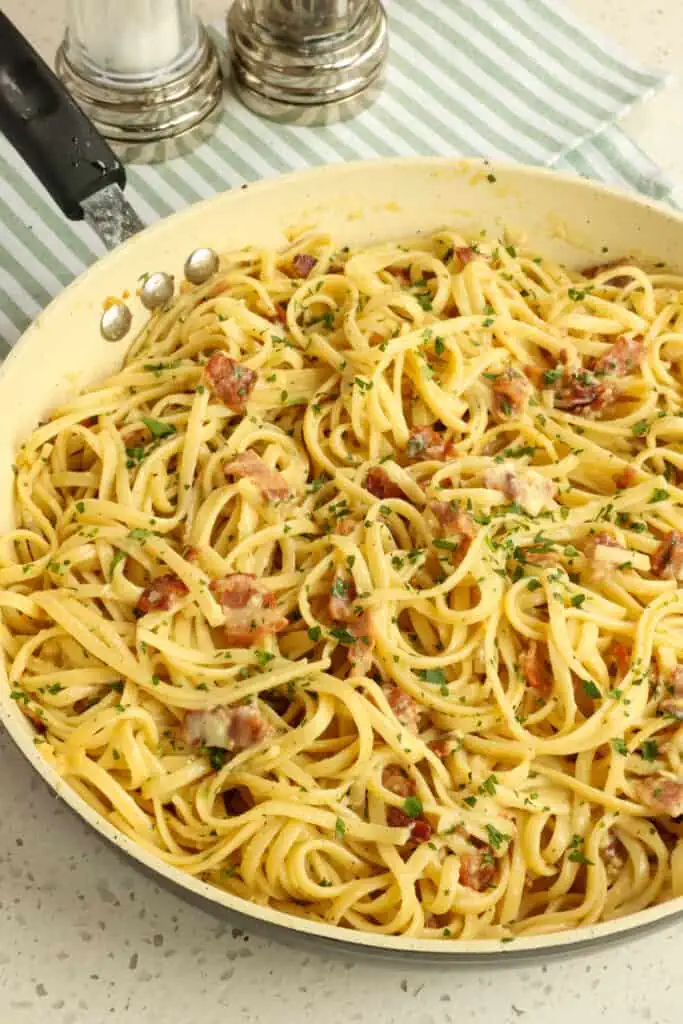 Pasta Carbonara is pasta mixed with thick pan-fried bacon or pancetta, a couple of tablespoons of the rendered fat, and a little bit of minced garlic. Then, a mixture of eggs, egg yolks, Parmesan, and a little cooking water is added and tossed quickly while the pasta is still very hot, creating a creamy sauce.  