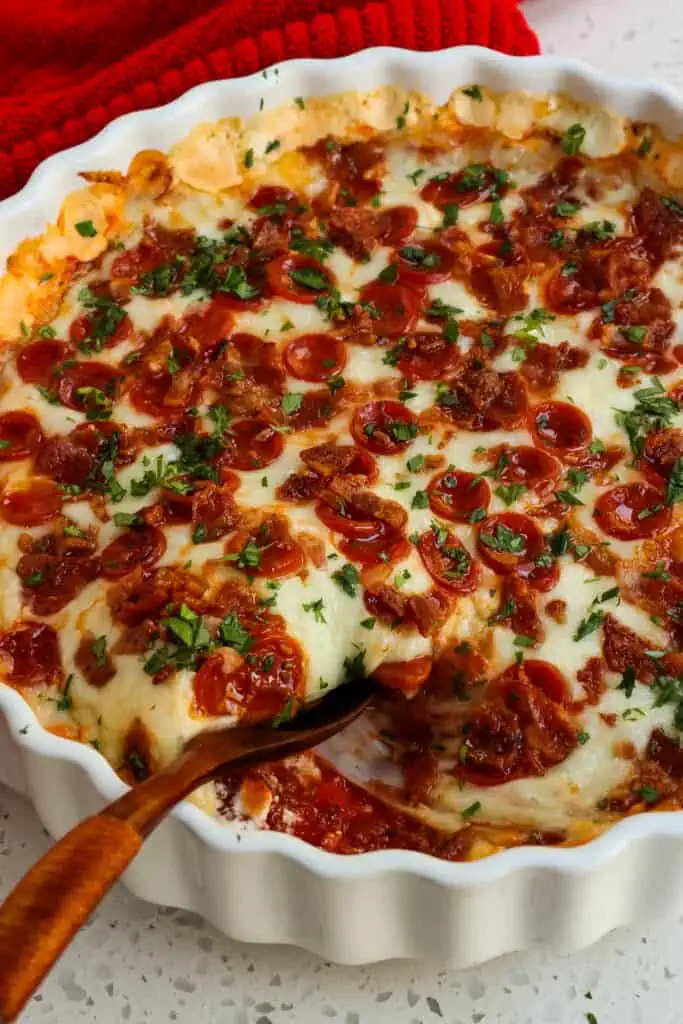 A quick and easy party favorite Pizza Dip made with cream cheese, mozzarella cheese, grated Parmesan cheese, a few common pantry spices, pepperoni, and bacon.