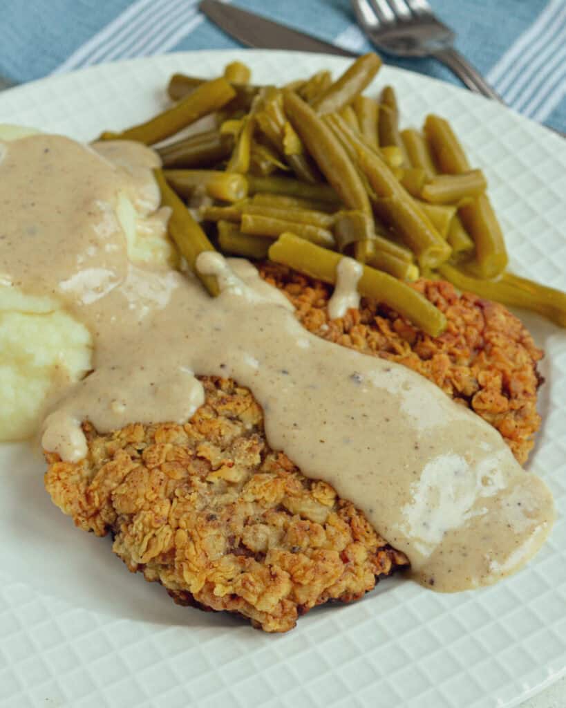 An overhead view of chicken fried steak with gravy on a serving plate.