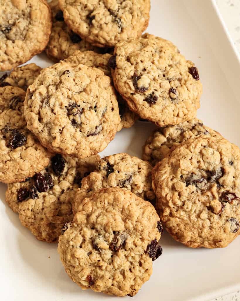 A close up view of oatmeal raisin cookies on a white serving platter. 