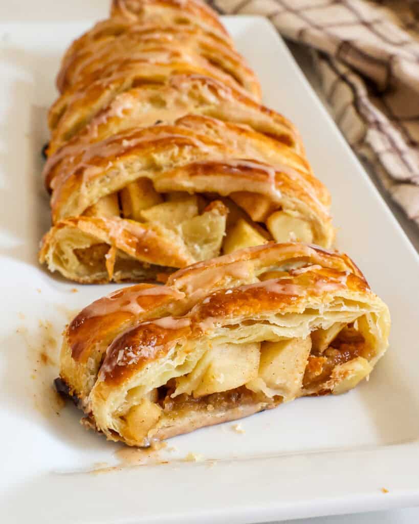 A sliced piece of apple strudel on a white platter.