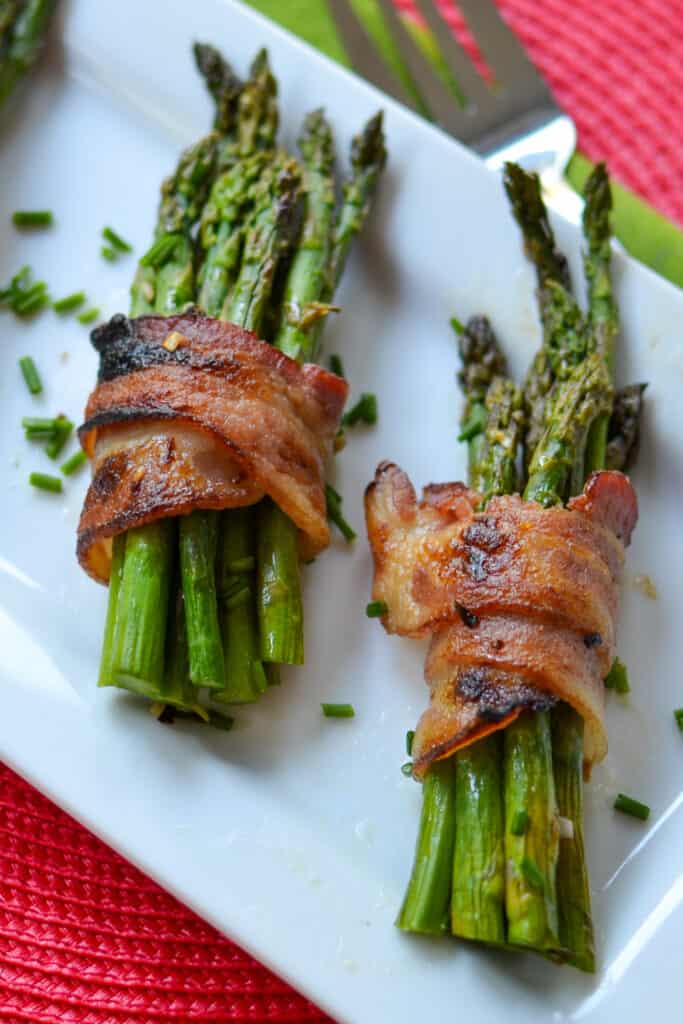 These Oven Bacon Wrapped Asparagus bundles are an easy and quick side dish to assemble. Fresh asparagus spears are wrapped with a strip of bacon, basted with a honey mustard vinaigrette, and baked to golden crispy tender perfection.  