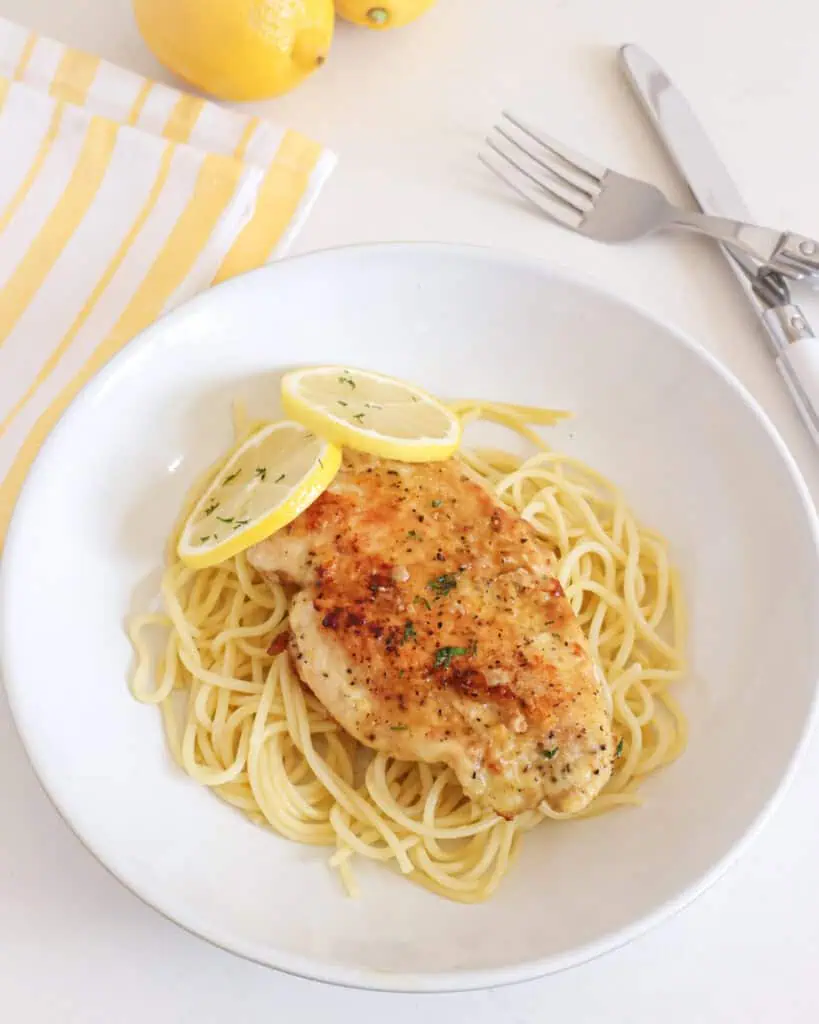 Lemon pepper chicken breast over thin spaghetti in a single serving bolw. 