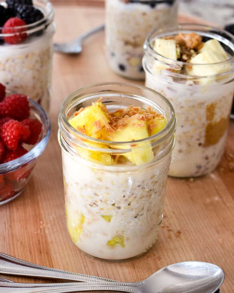 One of the flavor variations, pineapple and toasted coconut flakes overnight steel cut oats in a mason jar on a cutting board.