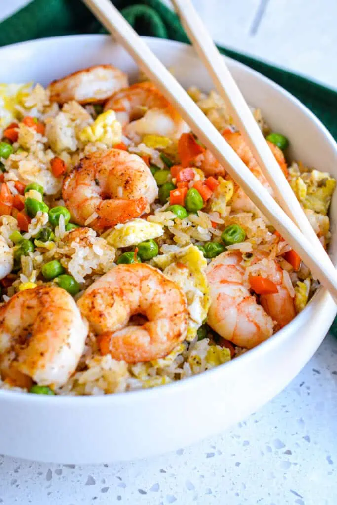 Tasty tender shrimp are nestled in perfectly seasoned fried rice with carrots, peas, onions, and fluffy eggs.