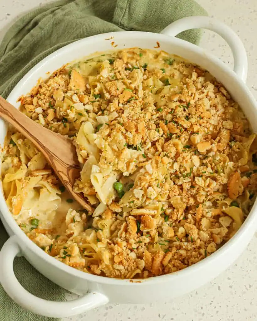 Eine Draufsicht auf eine Auflaufform voller Thunfisch-Nudel-Auflauf mit einem Holzlöffel darin.
