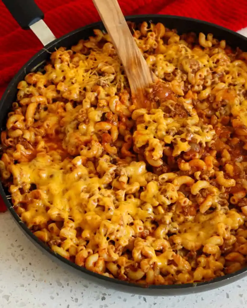 A large skillet full of beefaroni with melted cheddar over the top. 