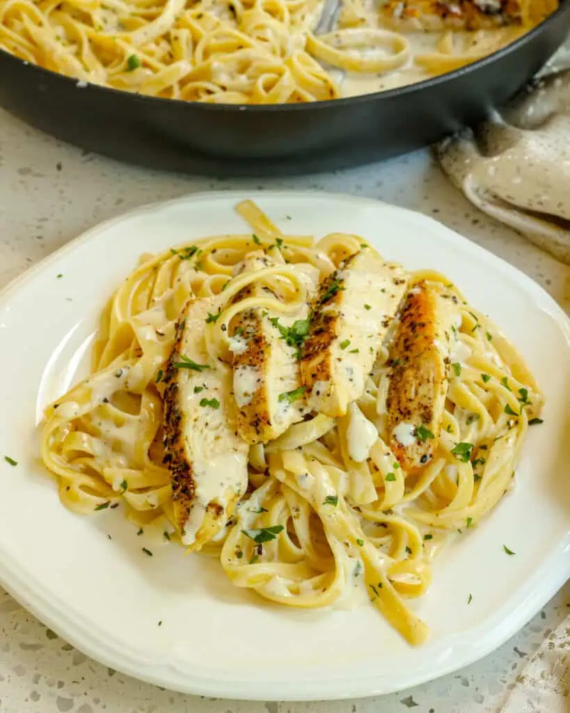 A deliciously easy cream Chicken Alfredo recipe made with golden brown seasoned chicken breast, fettuccini pasta, and a luscious alfredo cream sauce made with heavy cream and freshly grated Parmesan Cheese. 