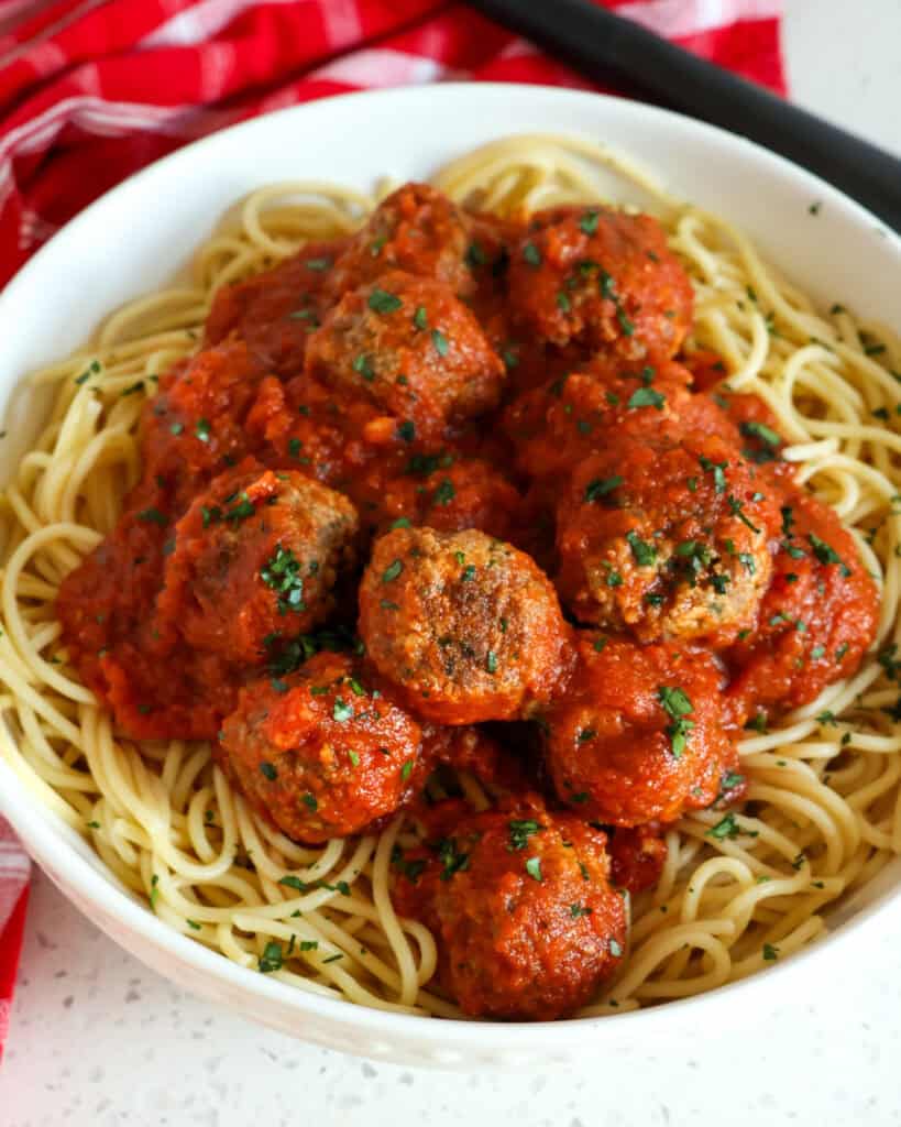 A close up view of spaghetti and meatballs in a white serving bowl.