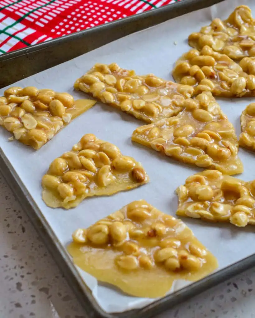 Peanut brittle pieces on a baking sheet covered with parchment paper. 