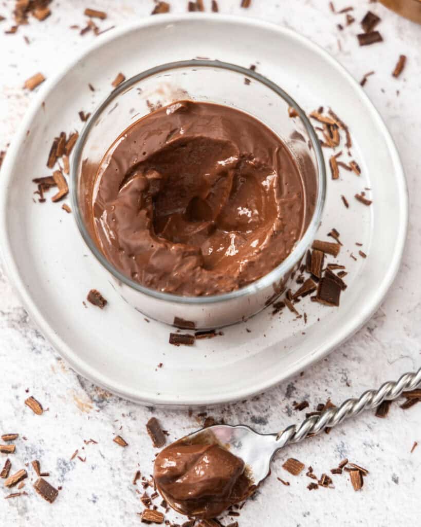 An overhead view of chocolate pudding with whipped cream and chocolate shavings.