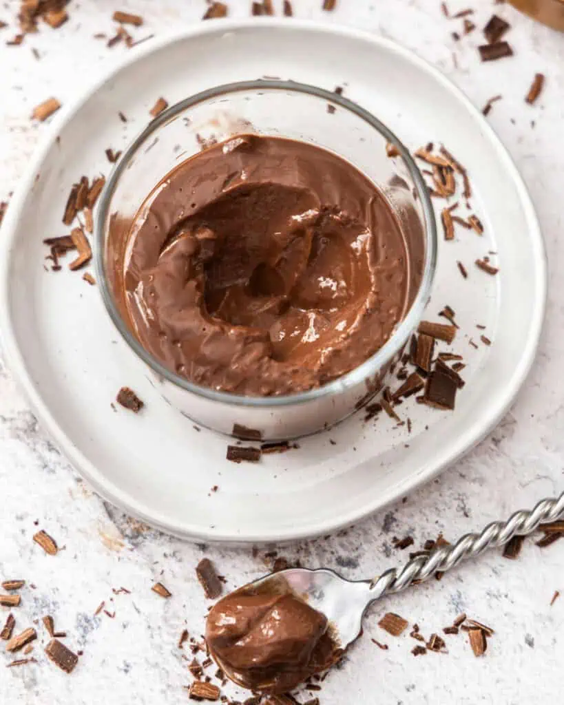 An overhead view of chocolate pudding with whipped cream and chocolate shavings. 