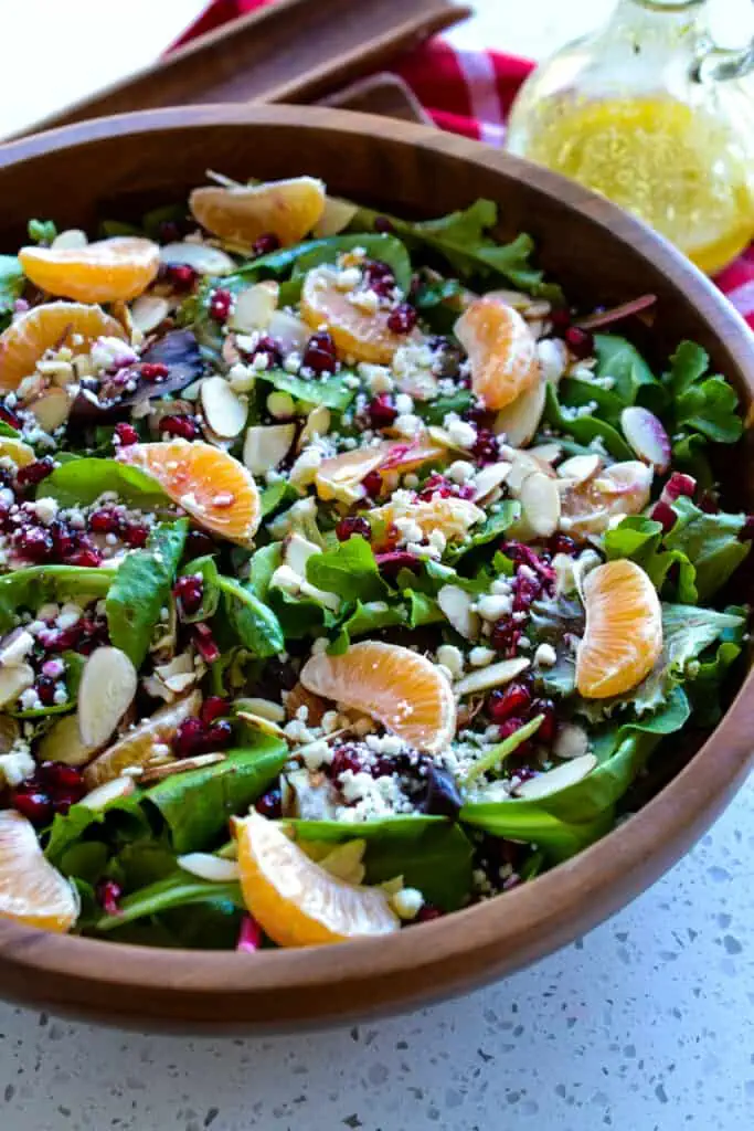This delicious Christmas Salad brings spring greens together with sliced almonds, feta cheese, mandarin oranges, and pomegranate arils, all drizzled with a tangy Honey Mustard Champagne Vinaigrette.