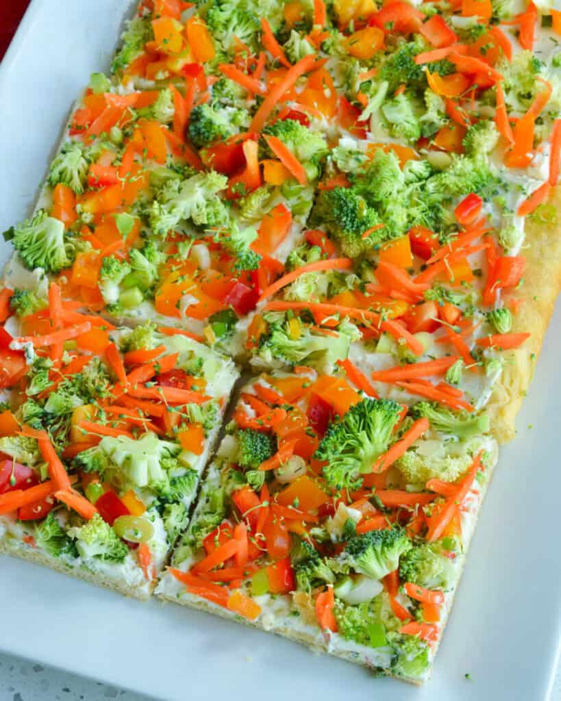 An overhead view of crescent roll pizza on a white serving platter.