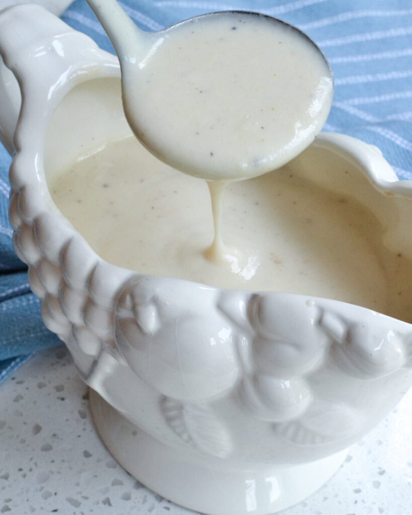 A ladle full of smooth white country gravy. 