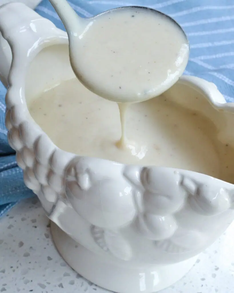 A ladle full of smooth white country gravy.