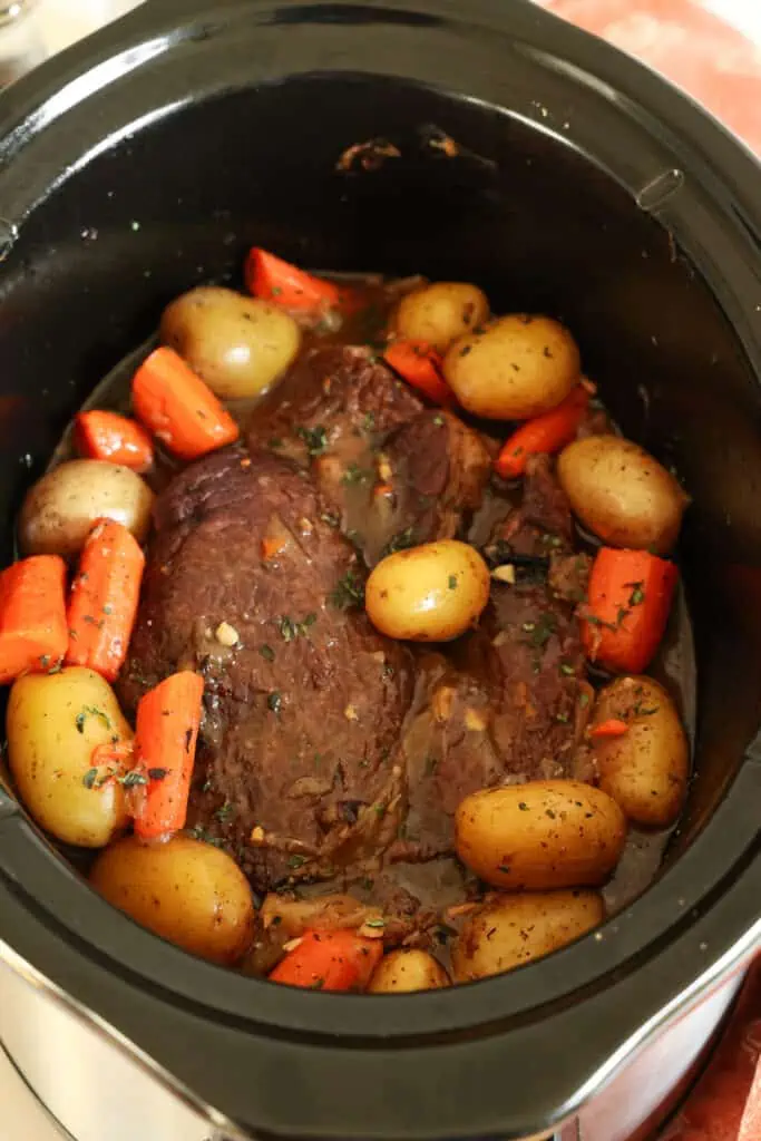 Slow cooker pot roast in a slow cooker with potatoes and carrots. 