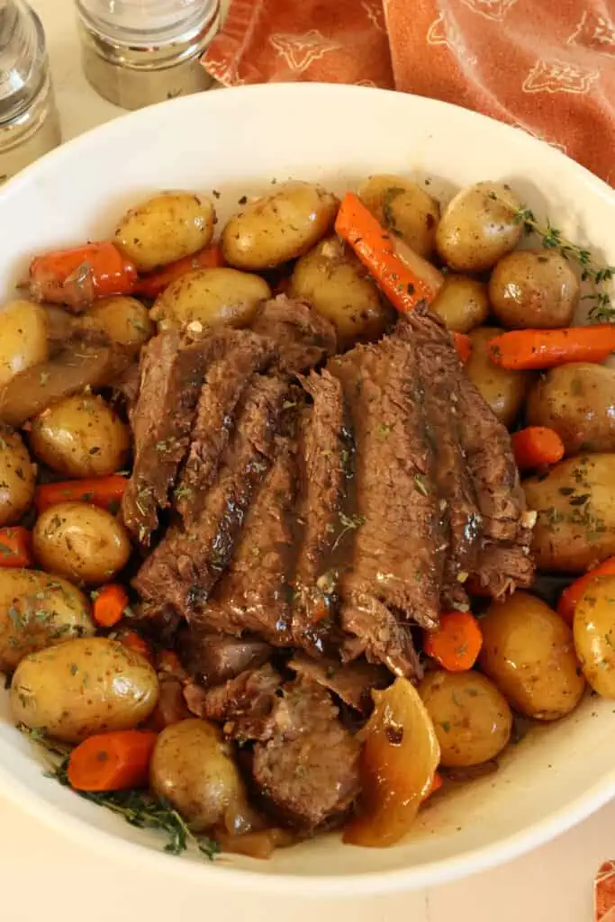 This Slow Cooker Pot Roast Recipe combines slow-cooked tender melt-in-your-mouth beef chuck roast with onions, carrots, and potatoes and a perfect blend of flavorful spices in a rich brown gravy.