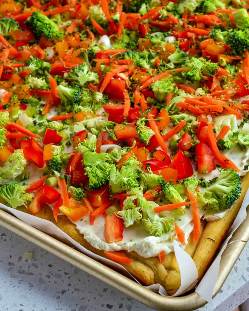 Cold veggie crescent roll pizza on a baking sheet. 