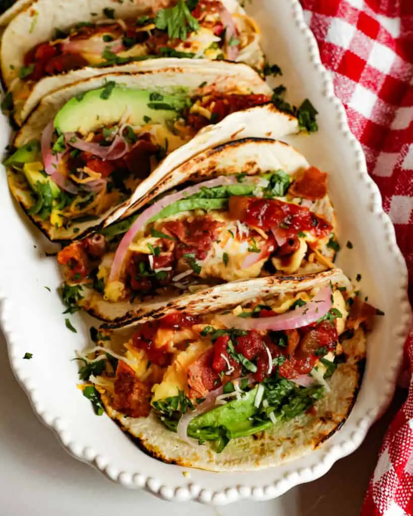 These Breakfast Tacos are loaded with bacon, scrambled eggs, cheddar cheese, and Monterey Jack Cheese, all wrapped in a tortilla and topped with salsa, avocado, pickled red onions, and chopped fresh cilantro.
