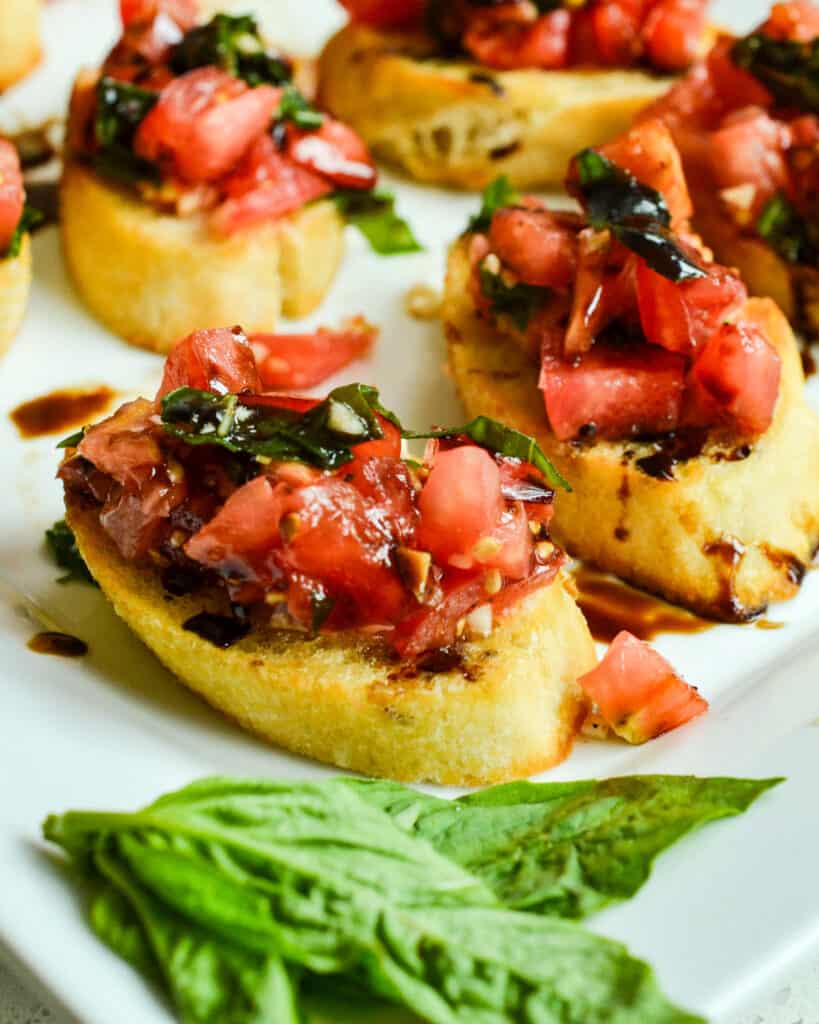 An easy garden fresh bruschetta recipe combining sun ripened tomatoes, sweet basil, and garlic all served on toasted baguette slices with a drizzle of balsamic glaze.