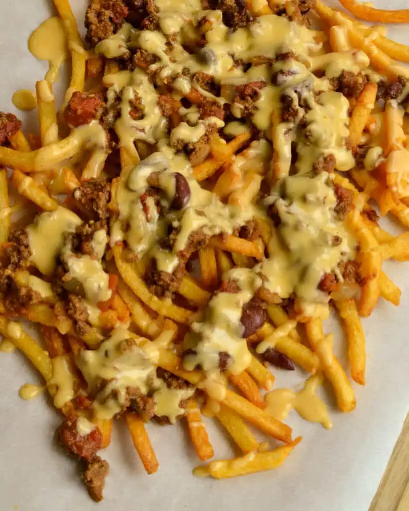 Scrumptious Chili Cheese Fries made with a hearty thick beef chili and topped with a lusciously creamy cheddar cheese sauce. 