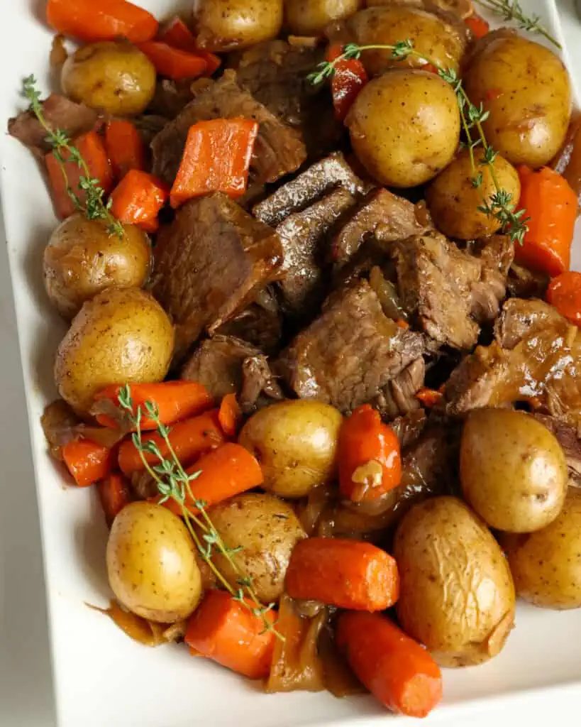Arrange the pot roast and cooked veggies on a platter with sprigs ot thyme and rosemary. 