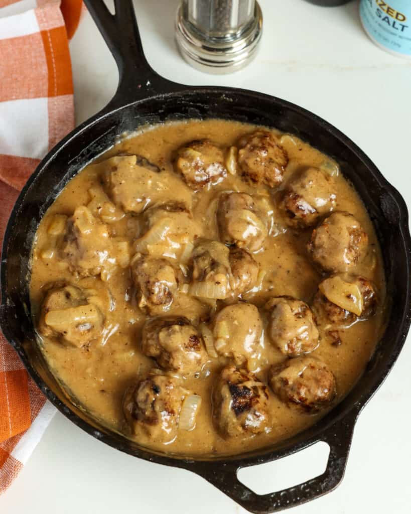 These quick and easy homemade meatballs are pan-fried with onions and smothered in a smooth and creamy gravy made with the pan drippings and seasoned with cracked pepper and chopped fresh thyme.