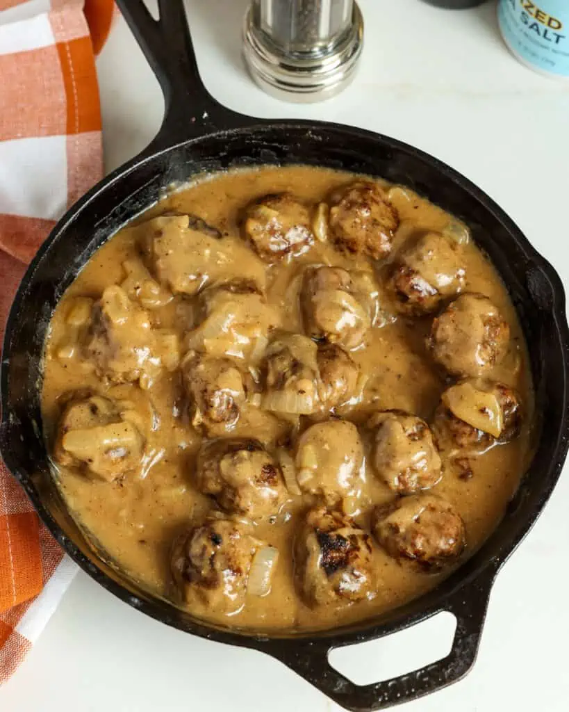 Diese schnell und einfach selbstgemachten Fleischbällchen werden mit Zwiebeln in der Pfanne gebraten und mit einer glatten, cremigen Soße aus Bratensaft übergossen und mit gemahlenem Pfeffer und gehacktem frischem Thymian gewürzt.