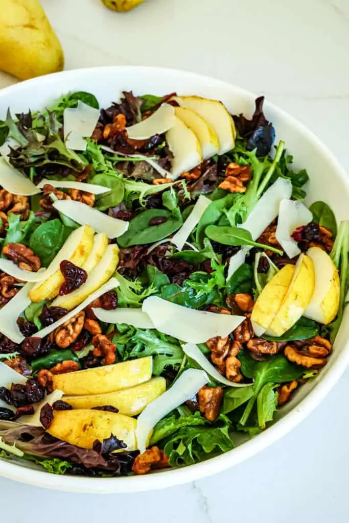 This Pear Salad combines candied walnuts, mixed greens, fresh pears, dried cranberries, and shaved Parmesan cheese, all drizzled with a homemade balsamic vinaigrette. 