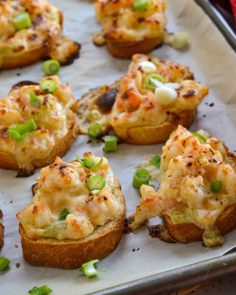 How to Make Shrimp Toast A close up view of shrimp toast on a parchment covered baking sheet.