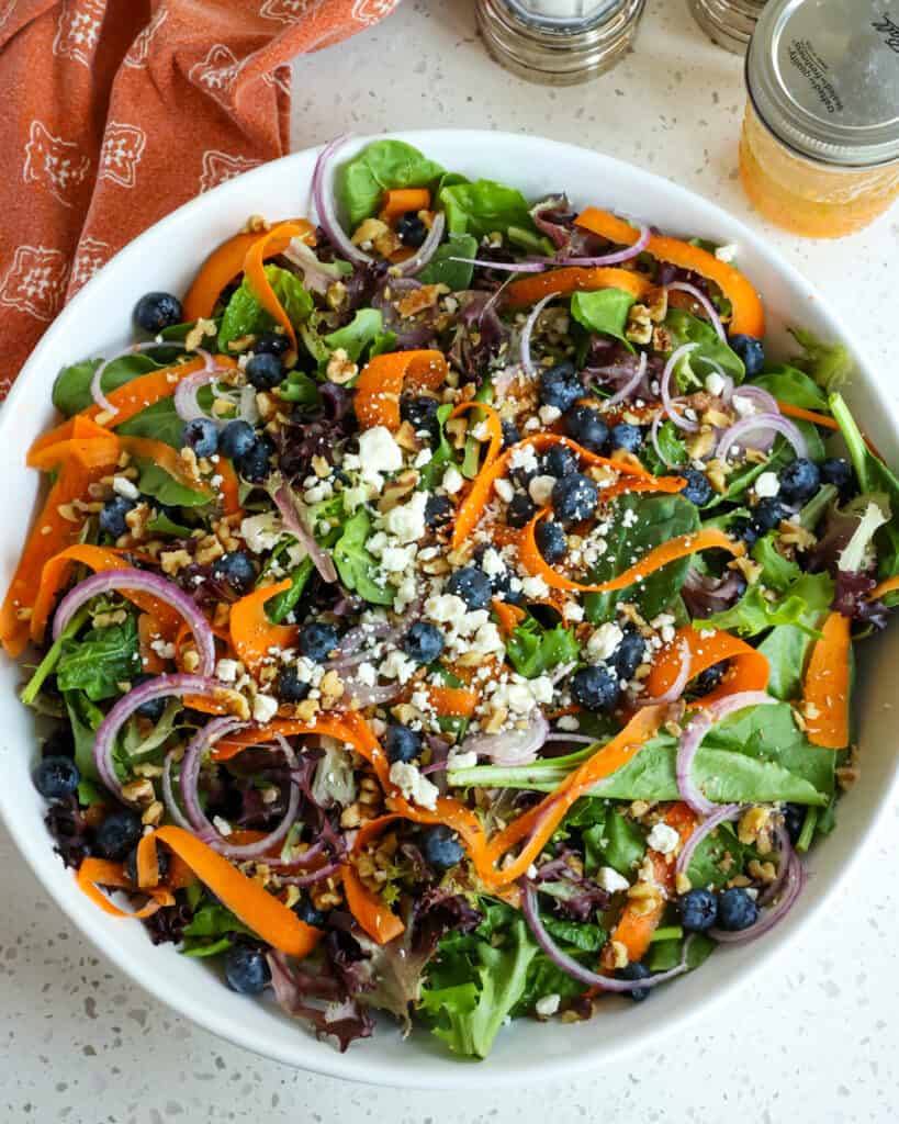 Enjoy this tasty Spring Mix Salad with shaved carrots, sweet blueberries, salty feta cheese, and rich walnuts all drizzled with a tangy sweet citrus vinaigrette.