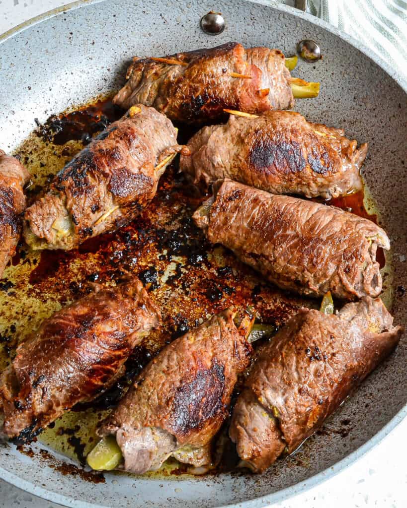 In a large skillet or Dutch oven over medium-high heat, heat vegetable oil and butter. Brown the beef rolls on all sides and add beef broth and pickle juice. Cover with foil and bake. Remove from the skillet and plate.