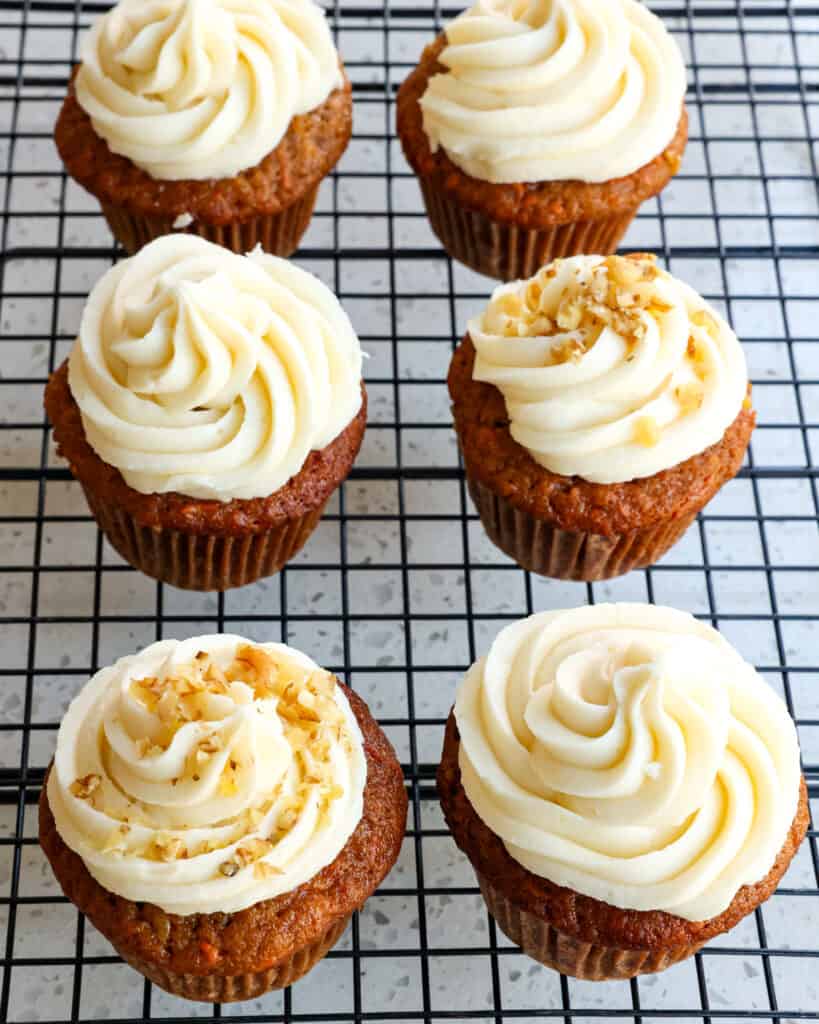 An overhead view of frosted carrot cake cupcakes on a wire cooling rack. 