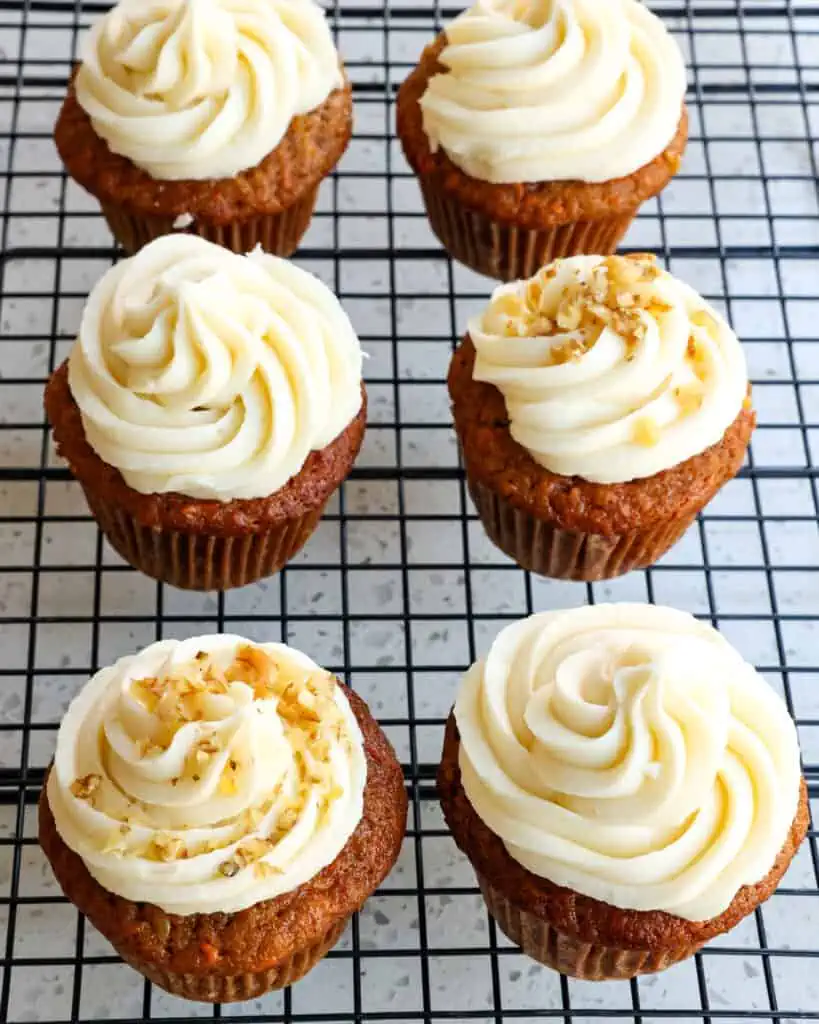 An overhead view of frosted carrot cake cupcakes on a wire cooling rack. 