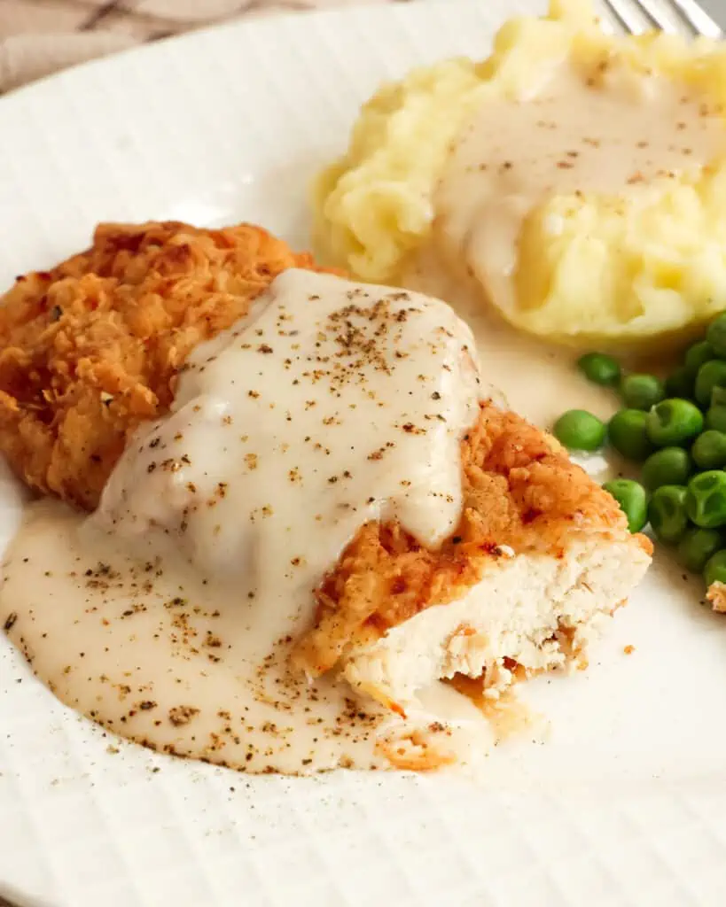 A quick and easy Southern Chicken Fried Chicken recipe with a crispy coating and creamy white country gravy. Enjoy it with mashed potatoes and sweet peas. 
